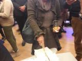 Общинската съветничка от ДСБ Марта Георгиева, която реже тортата с нож, а зад нея Борис Бонев води светски разговор.